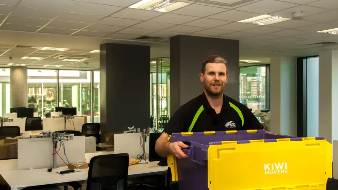 Kiwi Movers staff member carrying storage crate during office move in London